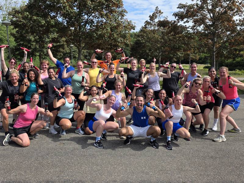 Een grote groep sporters juicht na een BRN-training buiten.