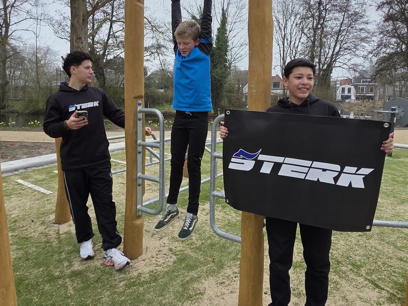 Kinderen van STERK Kids aan het klimrek, een van hen houdt het STERK-doek vast.